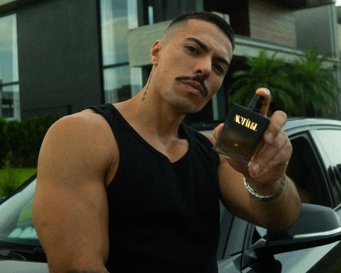 Fê Alves segurando um frasco do perfume Notável