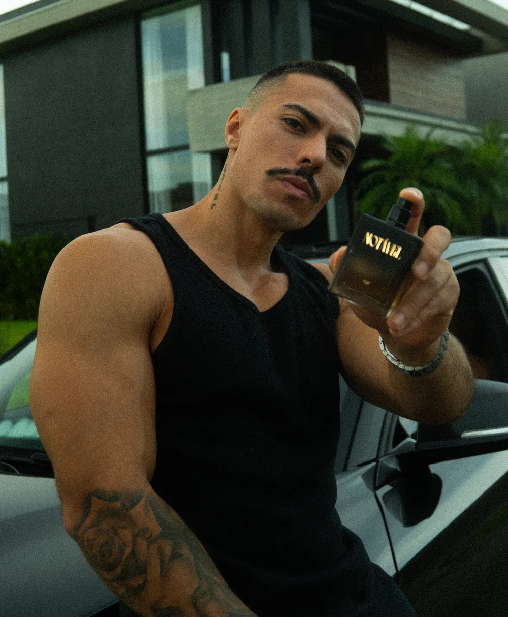 Fê Alves segurando um frasco do perfume Notável